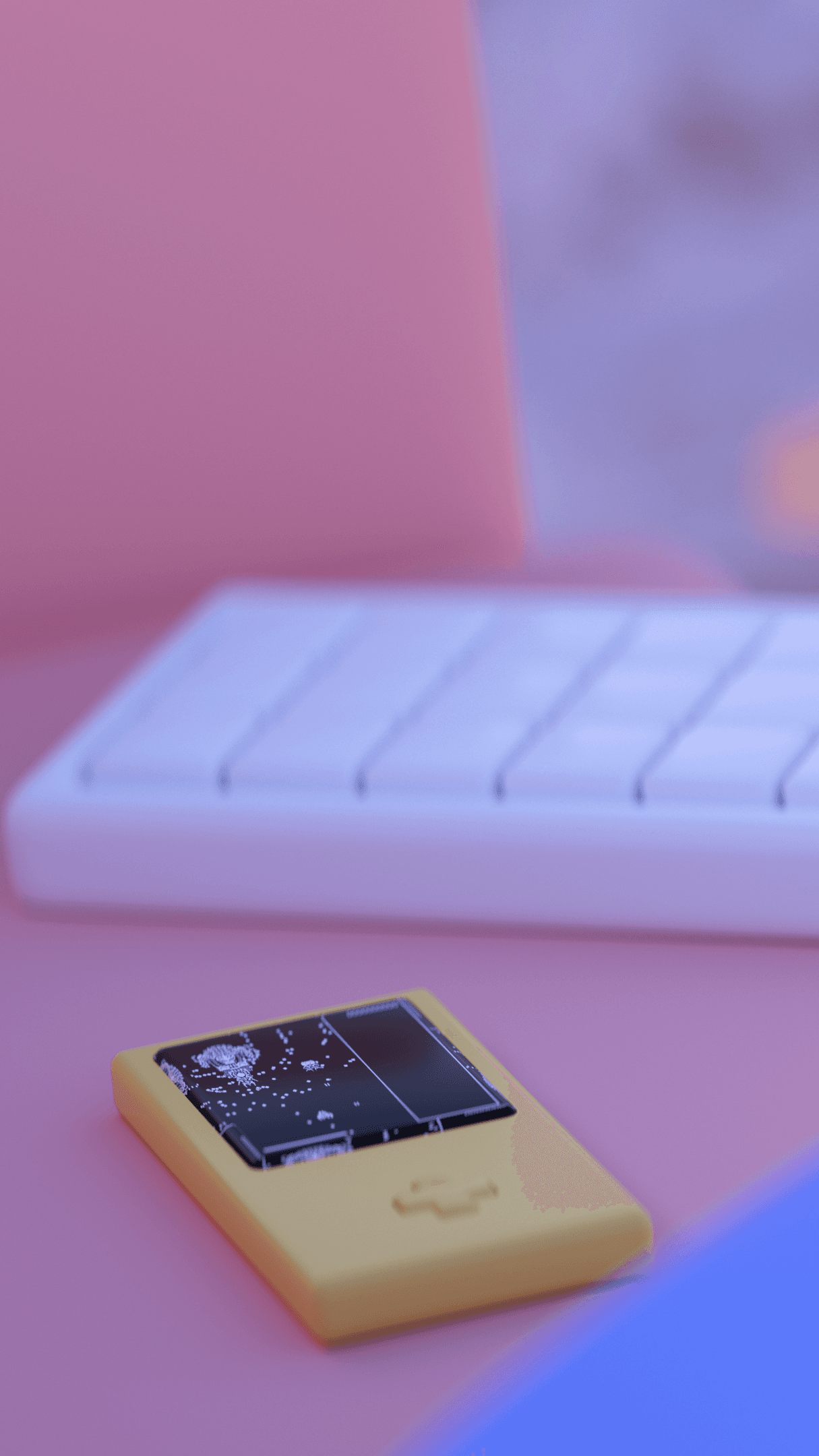 A close up of a gameboy next to a white keyboard both sitting on a pink couch on the beach.