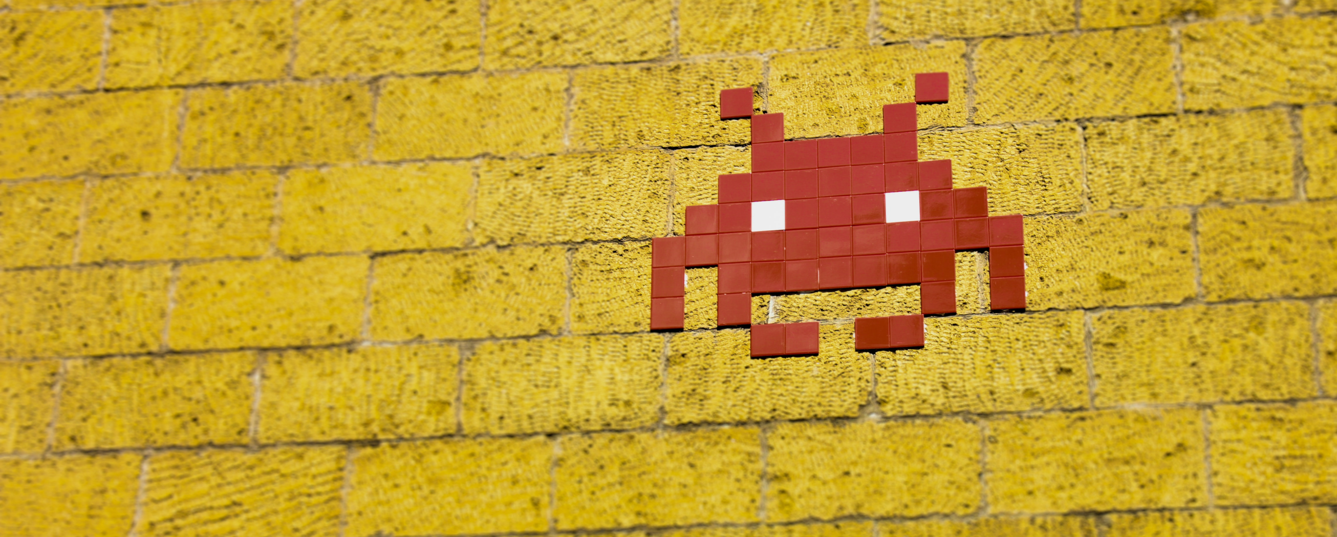 A Space Invaders red Crab (Medium Invader) on a yellow background.