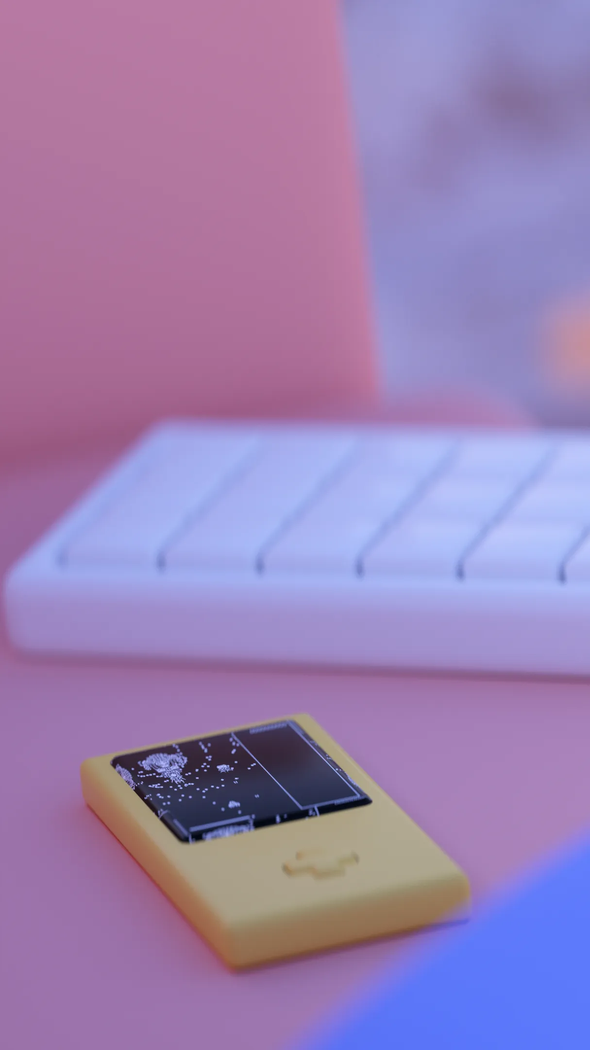 A close up of a gameboy next to a white keyboard both sitting on a pink couch on the beach.